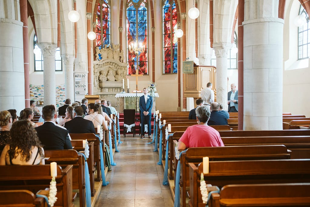 Bräutigam wartet mit allen Gästen in der Kirche.