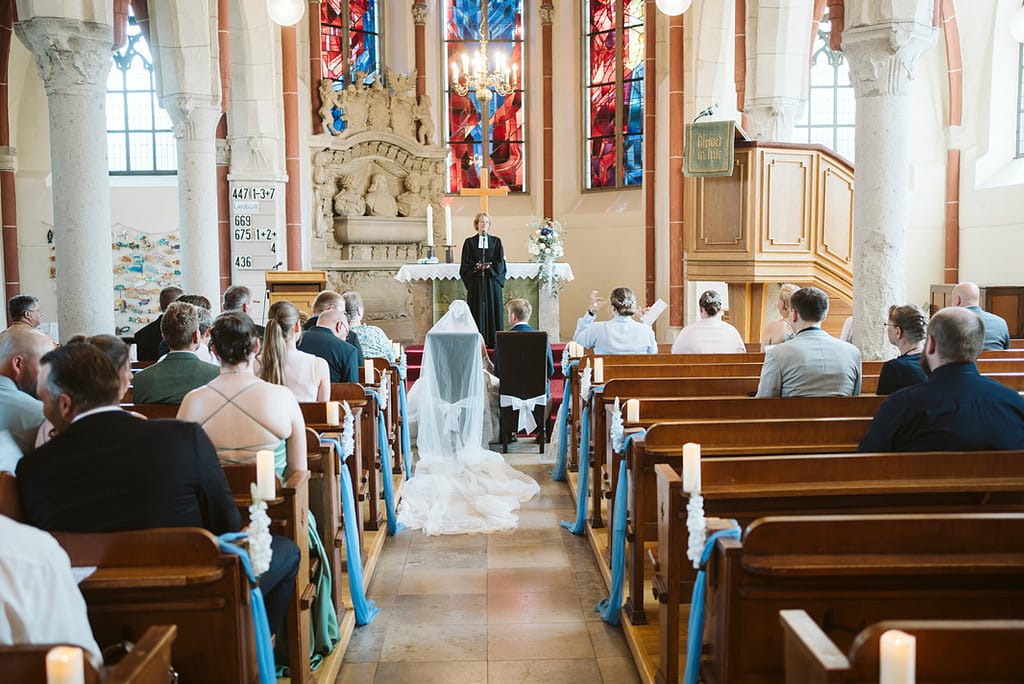 Ganze Hochzeitsgesellschaft fotografiert vom hinteren Teil des Kirchenschiffes.