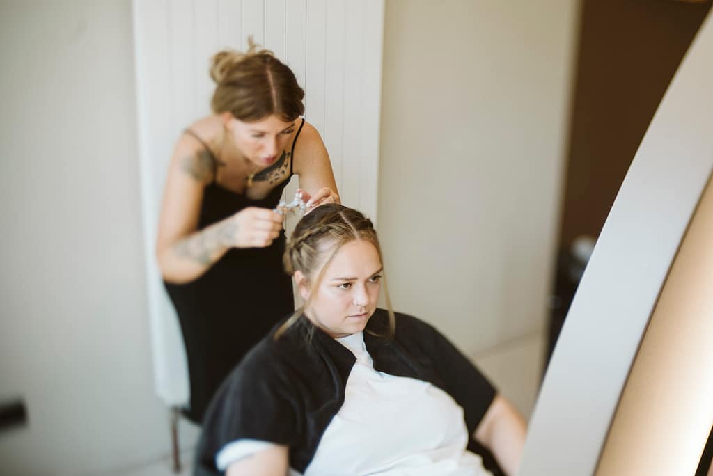Hairstylistin bei der Arbeit am Styling der Brautjungfer.