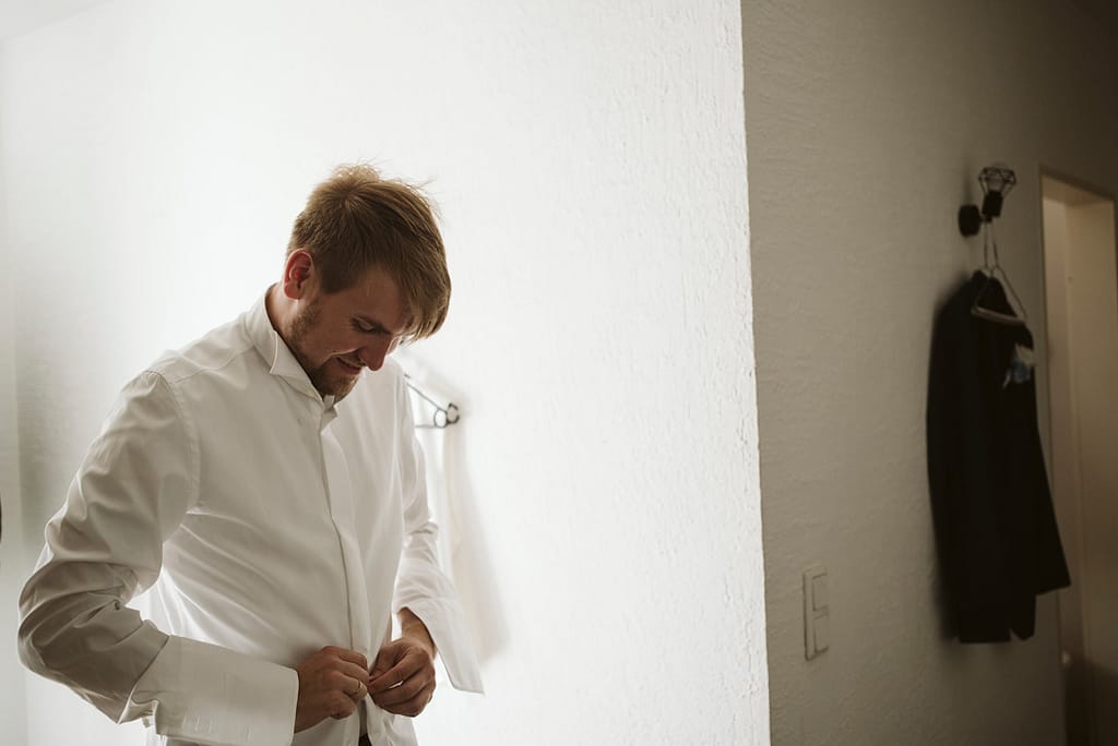Bräutigam beim Anziehen des weißen Hemdes.