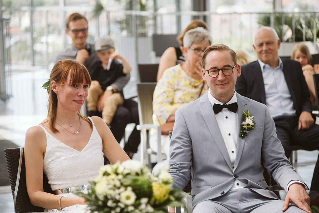 Das Brautpaar zusammen am Tisch bei der Trauung. Die Braut ist sichtlich emotional.