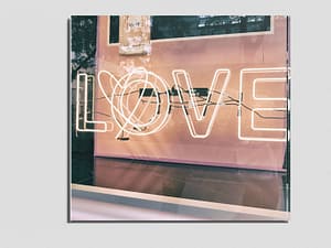 Fotografie eines leuchtenden Schriftzugs "Love". Dieser ist auch auf dem Gutschein zu sehen.